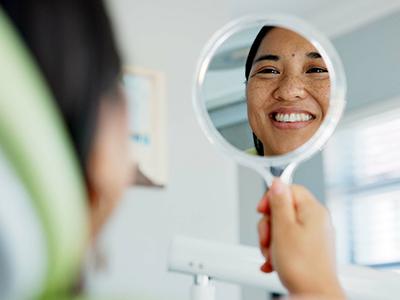 Woman smiling in the mirror after dental treatment