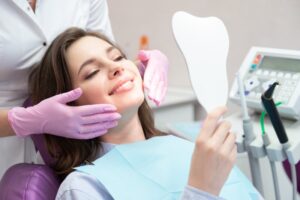 Young woman in the dentist's chair smiling into a mirror.