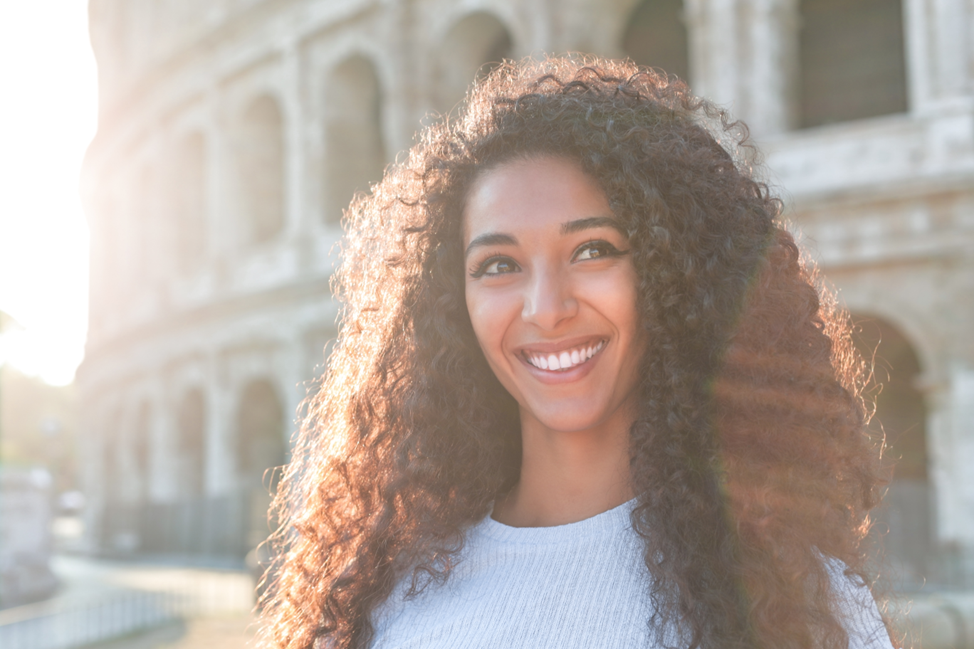 young woman smiling in front of Roman Colosseum 