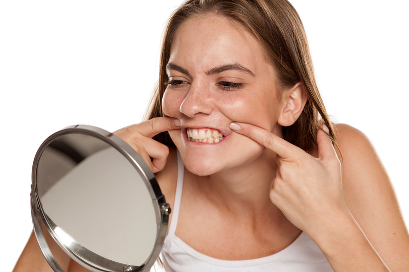 Patient looking in mirror thinking about getting cosmetic dentistry